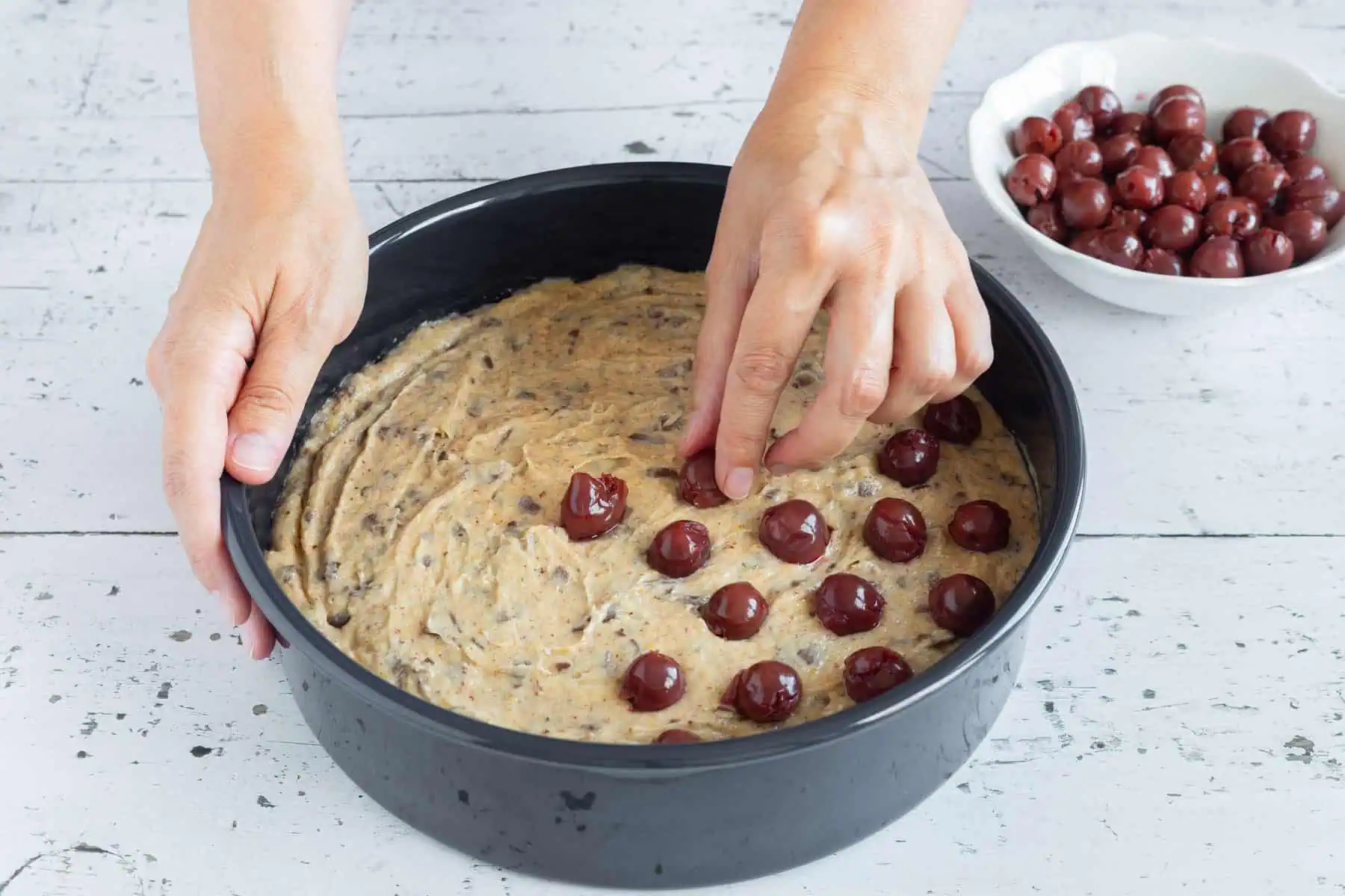 Kirschen werden auf einem Nuss Schoko Kuchen verteilt.