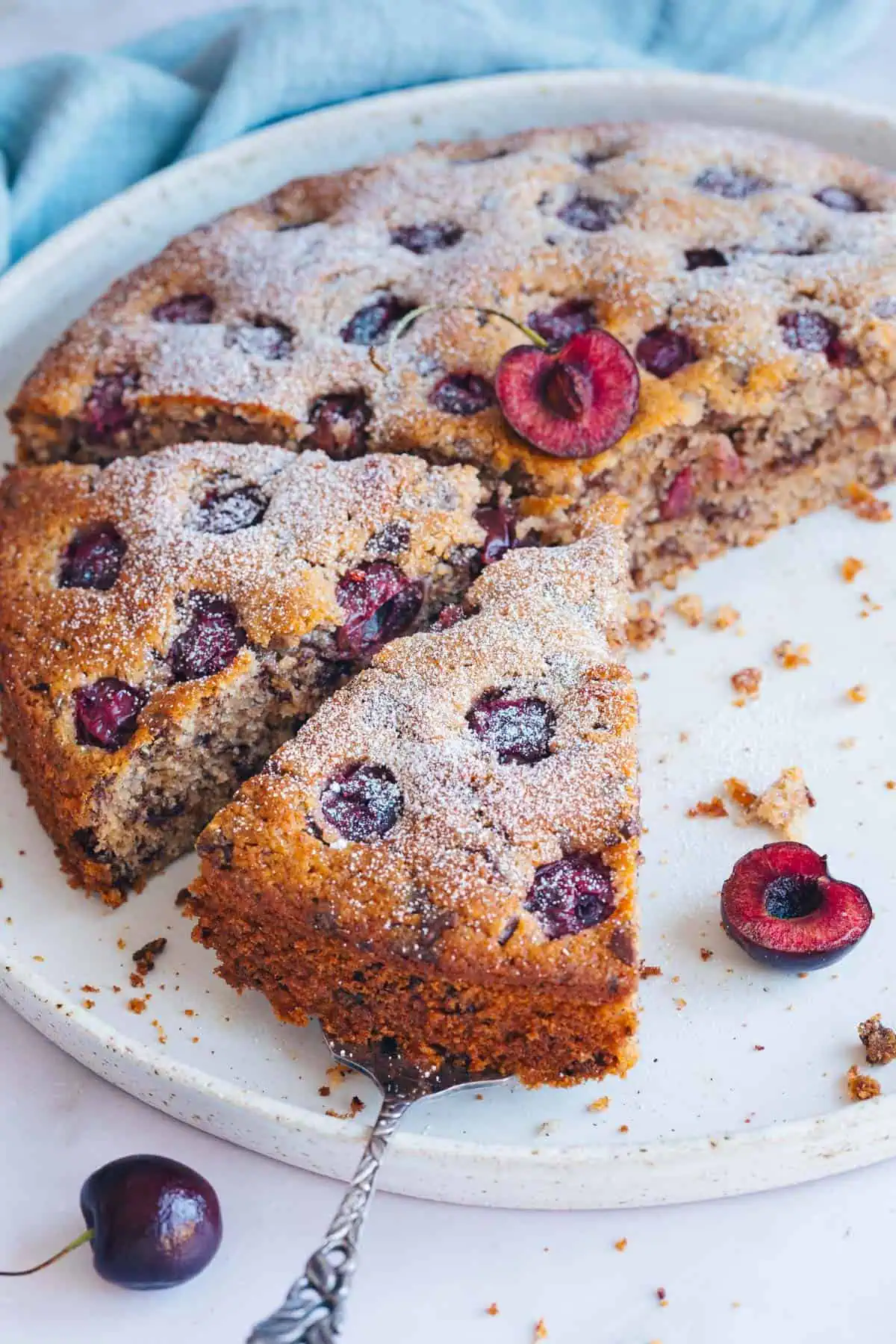 Aufgeschnittener Kirschkuchen mit Nüssen und Schokolade auf einem Kuchenteller.